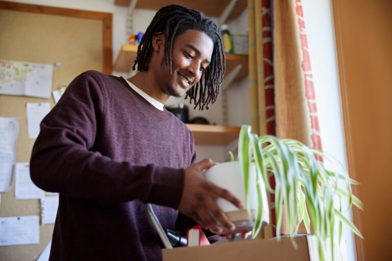 A student checking off items on a college apartment move in checklist while unpacking a first-night survival box.