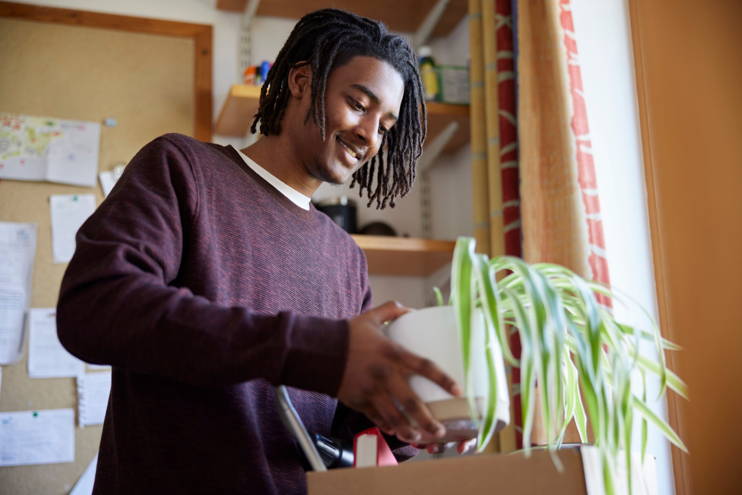 A student checking off items on a college apartment move in checklist while unpacking a first-night survival box.